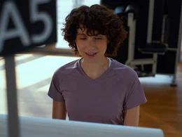 Eine Frau mit lockigem Haar blickt konzentriert auf den Monitor einer Kieser Trainingsmaschine zur Überprüfung der Übungsausführung.