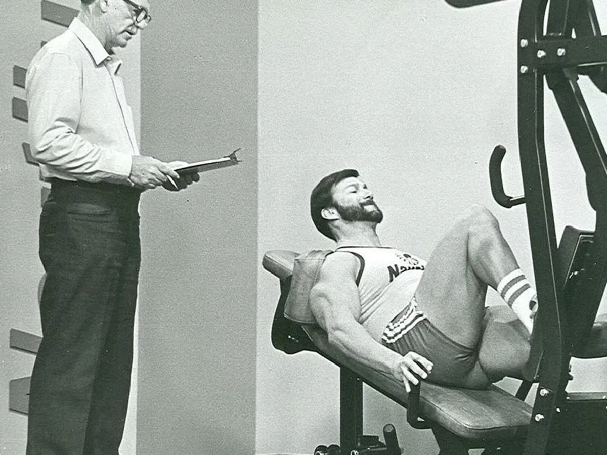 Historische Aufnahme einer kontrollierten Trainingseinheit an der Beinpresse unter wissenschaftlicher Beobachtung und Dokumentation.