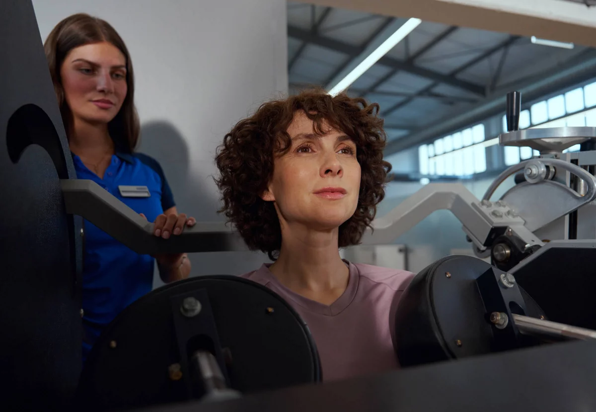 Eine Frau führt im Kieser-Studio an der CE-Maschine ein Nackentraining zur Stärkung der Nacken- und Rückenmuskulatur durch.