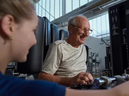 Ein lächelnder Senior beim Krafttraining bei Kieser – Sinnbild für die Unternehmensphilosophie von lebenslanger Vitalität und Muskelaufbau.
