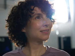Frau mit lockigen Haaren beim Krafttraining im Fitnessstudio, motiviert und konzentriert, gesundheitsorientiertes Training