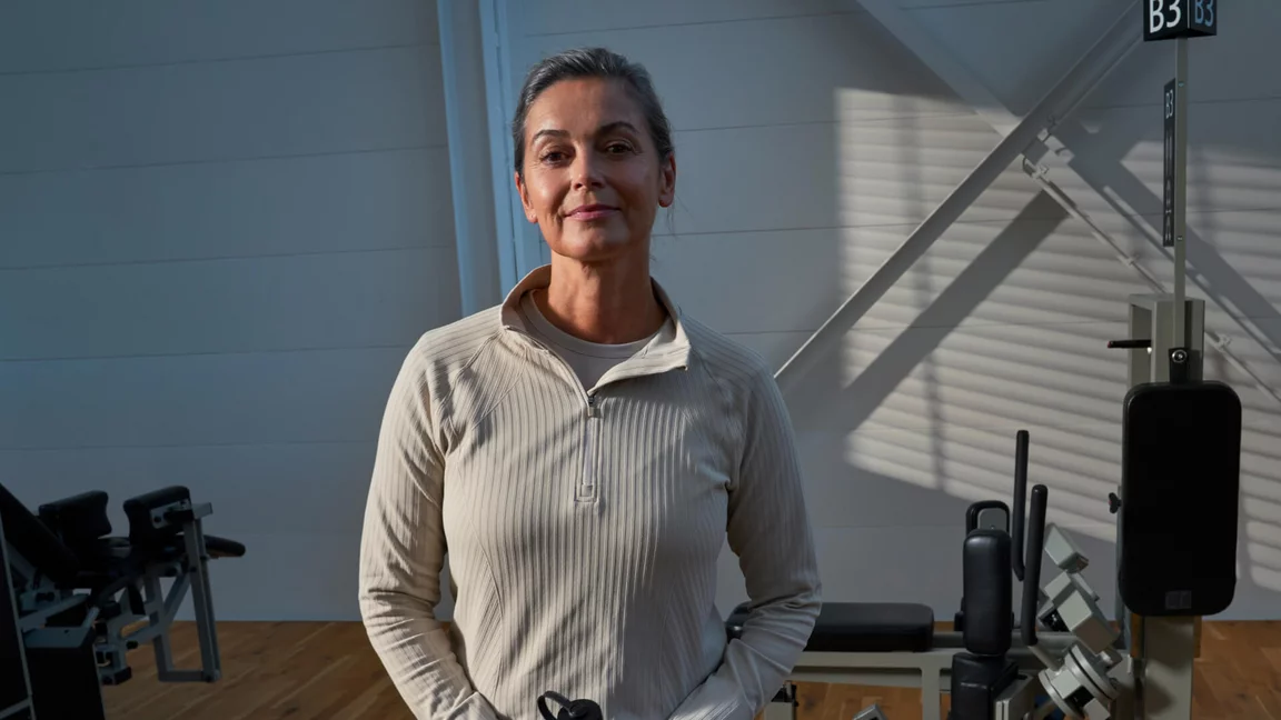 Trainierende Person in heller Trainingskleidung steht zwischen Krafttrainingsgeräten in einem Kieser Studio mit natürlichem Lichteinfall.