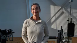 Trainierende Person in heller Trainingskleidung steht zwischen Krafttrainingsgeräten in einem Kieser Studio mit natürlichem Lichteinfall.