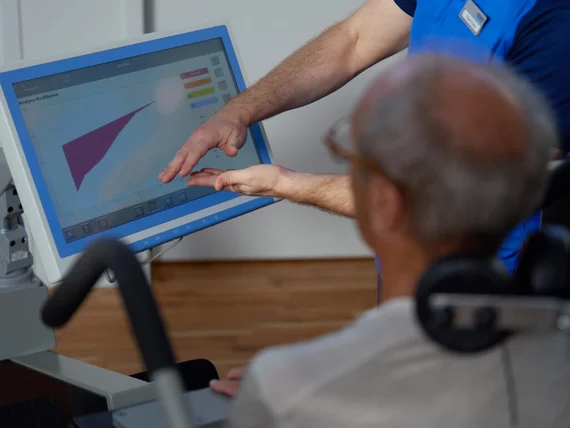 Ein Kieser-Instruktor erklärt einem Kunden die Ergebnisse seiner digitalen Rückenanalyse am Monitor zur Planung des individuellen Krafttraining-Programms.