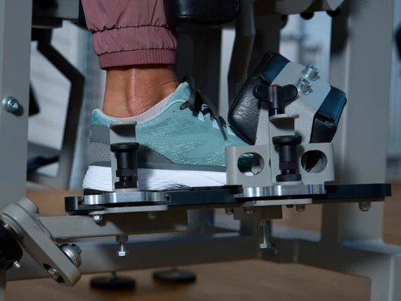 Nahaufnahme eines Fußes in einem Sportschuh in einer spezialisierten Kieser Maschine zur Stärkung der Sprunggelenke.