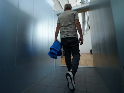 Ein Mann verlässt nach einem erfolgreichen Herz-Kreislauf-Training mit seinem Handtuch den modernen Kieser Trainingsbereich.