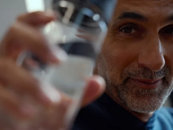 Ein zufriedener Trainierender hält eine Wasserflasche – Symbol für die wichtige Regeneration nach einem wissenschaftlich fundierten Herz-Kreislauftraining.