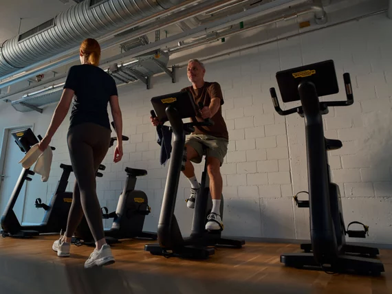 Zwei Trainierende an modernen Rad-Ergometern bei Kieser während eines individuell abgestimmten HIIT-Trainings.